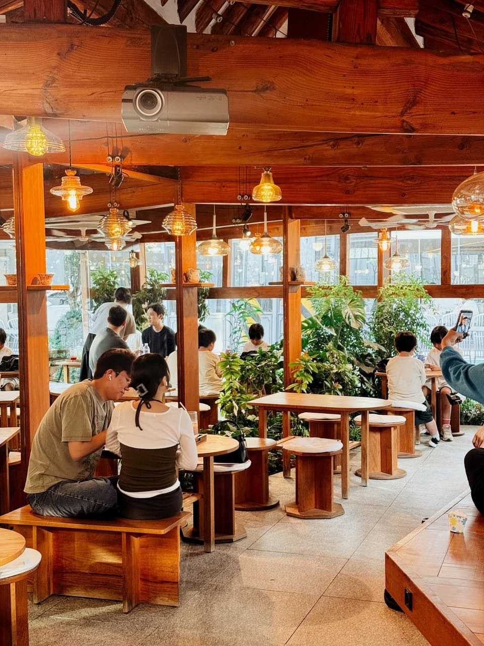People enjoying a warm wood-and-plants café in Seoul