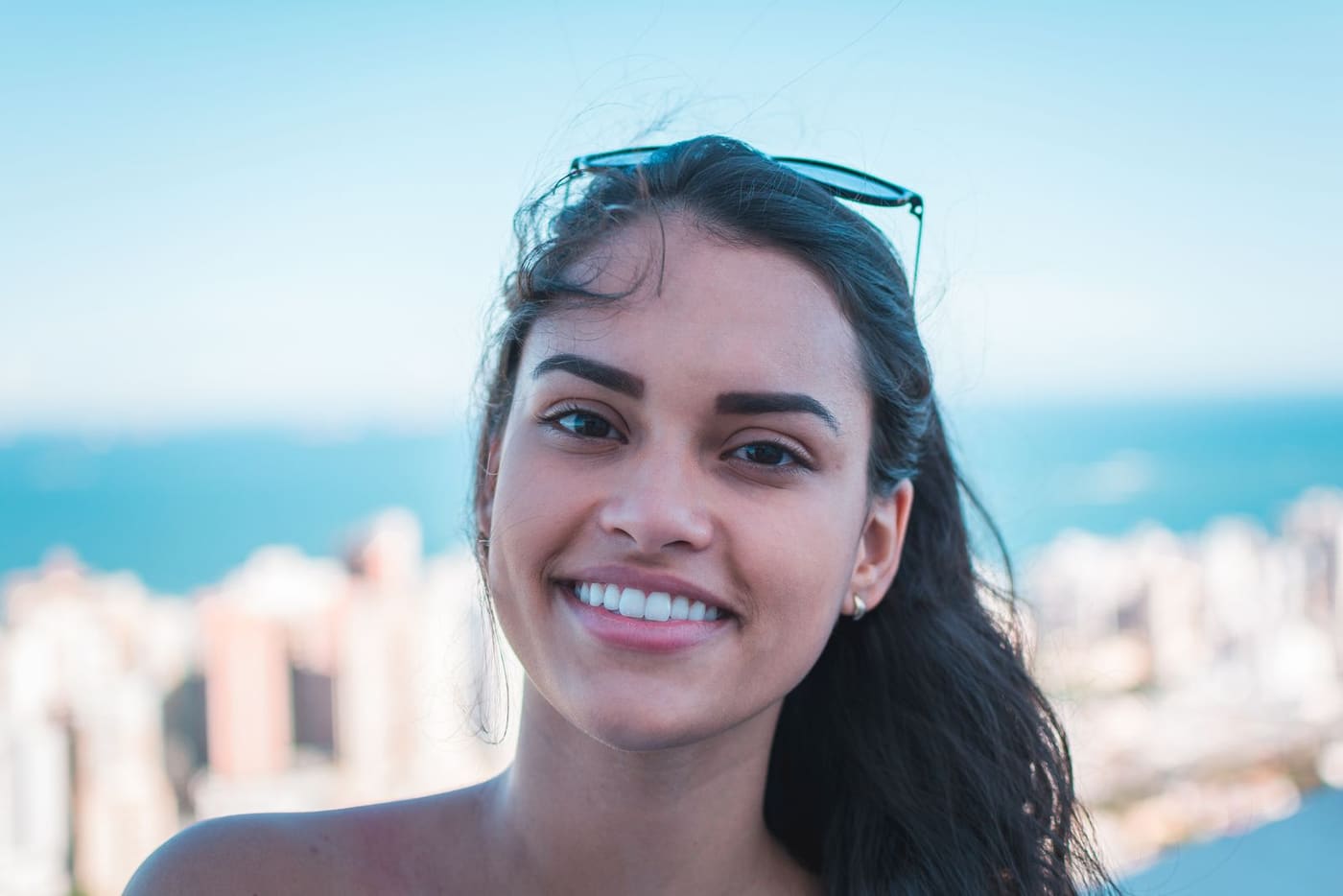 Smiling woman in daylight with sunglasses resting on her head